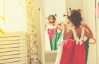 little girl child looks into the mirror and choose dresses